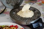 Waffelteig wird in ein Waffeleisen gefüllt.