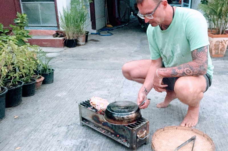 Nico Stanitzok bereitet Pizza auf dem Holzkohle-Grill in Chiang Mai zu.