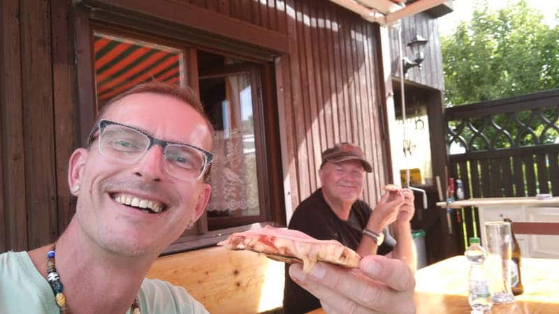 Nico Stanitzok und Herbert hocken im Garten und essen Pizza vom Grill.